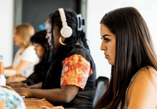 Four women are sitting at a desk working